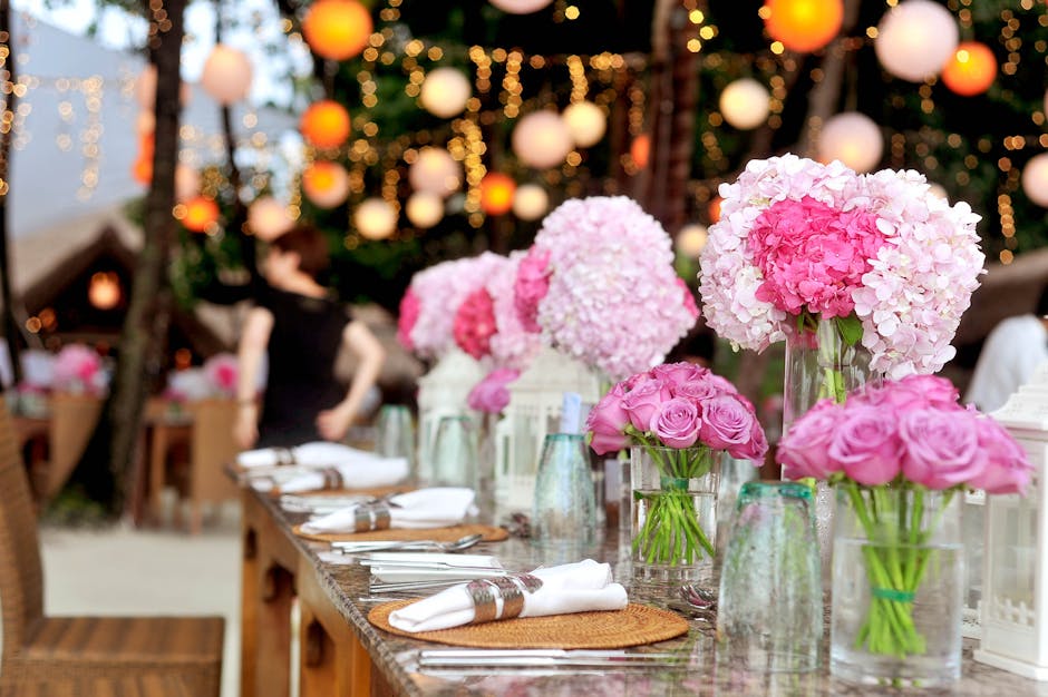 A long wooden dining table decorated with elegant floral arrangements for a wedding reception at Chadwell Heath High Road venue, featuring large pink hydrangea and rose bouquets in tall and small glas